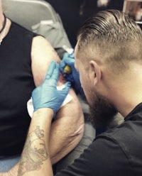 a man is getting a tattoo on his arm