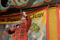 a man in a red jacket standing on a stage in front of a sign