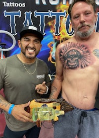 two men standing next to each other at a tattoo convention