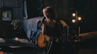 a woman singing and playing an acoustic guitar